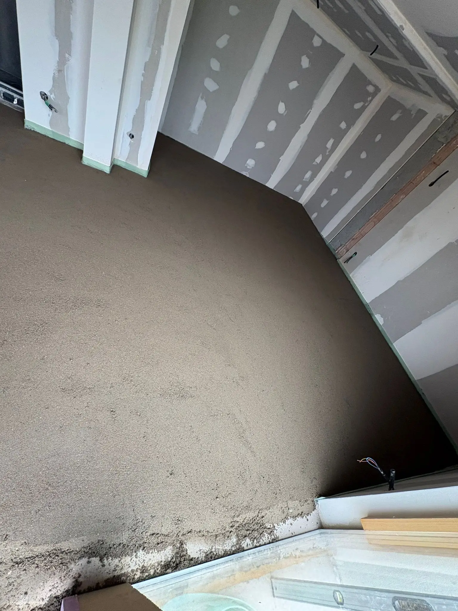 Chape sèche occupant toute une pièce sous rampant, plaques de plâtre jointoyées et bande périphérique verte visible en pied de cloison.