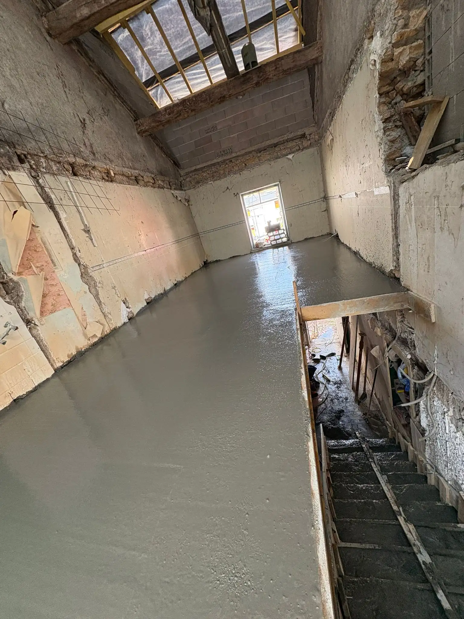 Coulage d’une dalle béton intérieure dans une pièce de maison ancienne en rénovation.