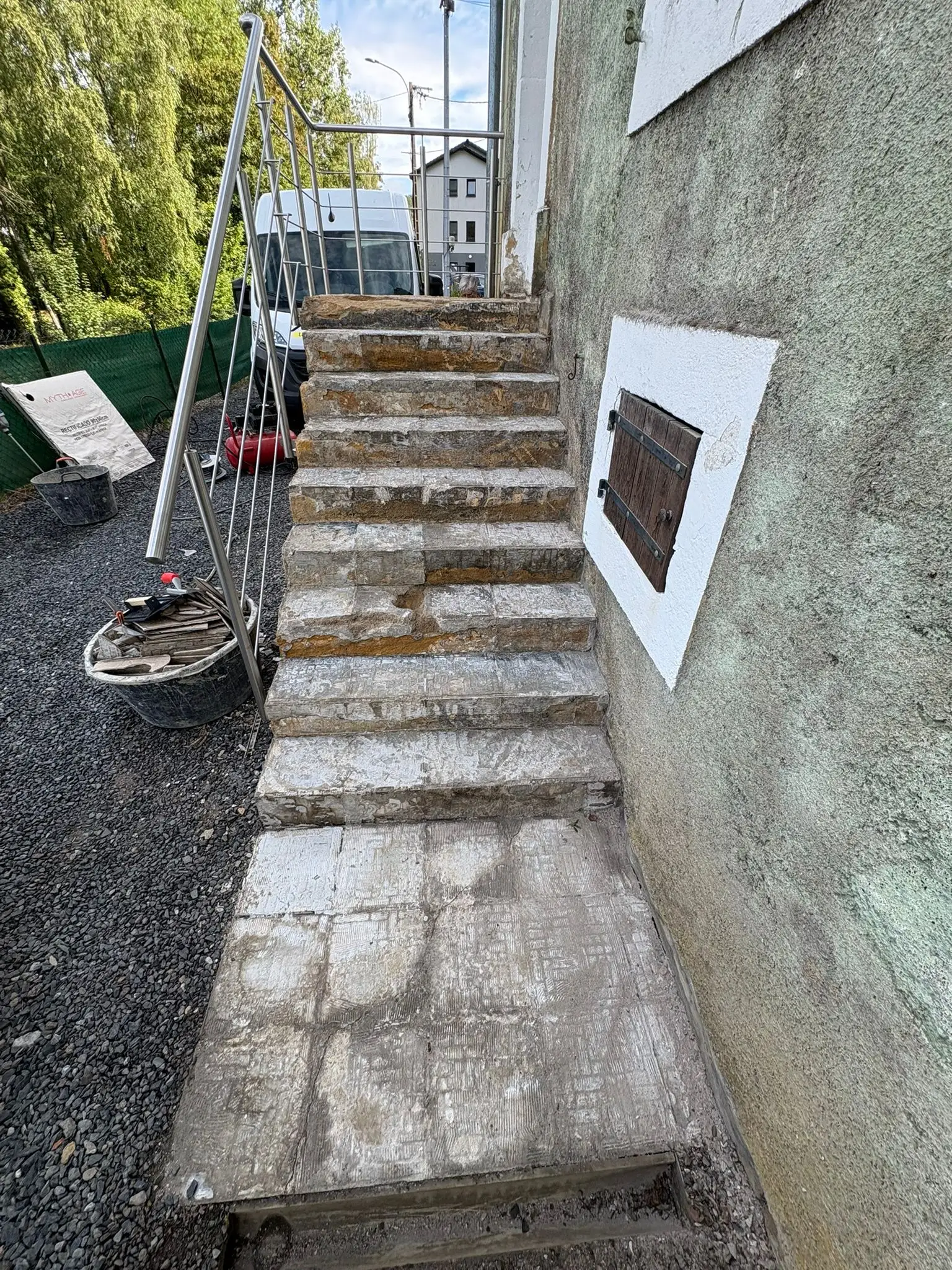 Escalier extérieur en pierre avant travaux, marches irrégulières et joints ouverts le long d’un mur enduit.